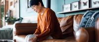 older asian woman sitting on couch in pain